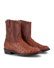 El VAQUERO VAQUERA Arrieta - Bota de Cierre Avestruz Nuez presenta textura de piel de avestruz marrón en el pie y piel lisa en la caña, desplegada sobre fondo blanco.