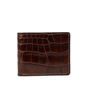 La VAQUERO VAQUERA La Reserva Alligator Alazán es una cartera de piel marrón con textura de piel de cocodrilo y ligeros pespuntes en los bordes, lucida sobre un fondo blanco liso.