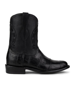 La Murrieta American Alligator Negro de VAQUERO VAQUERA es una bota negra a media pantorrilla con caña cosida, tira de tiro, tacón bajo y auténtico acabado texturizado de piel de cocodrilo americano en el pie y el talón.