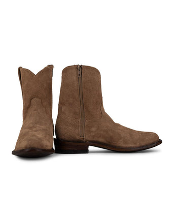 Un par de botas VAQUERO VAQUERA Arrieta Bota de Cierre Gamuza Bentley de color marrón claro: una en posición vertical para mostrar la cremallera lateral, la otra de lado dejando ver la suela y la parte delantera. Ambas presentan un estilo vaquero mexicano auténtico ligeramente desgastado.