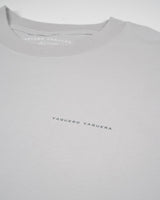 La Houston Tee de VAQUERO VAQUERA es una camiseta unisex de color gris claro con el nombre de la marca en mayúsculas pequeñas en el pecho. Su tejido transpirable y su cuello redondo clásico aportan comodidad diaria con un sutil estilo western.