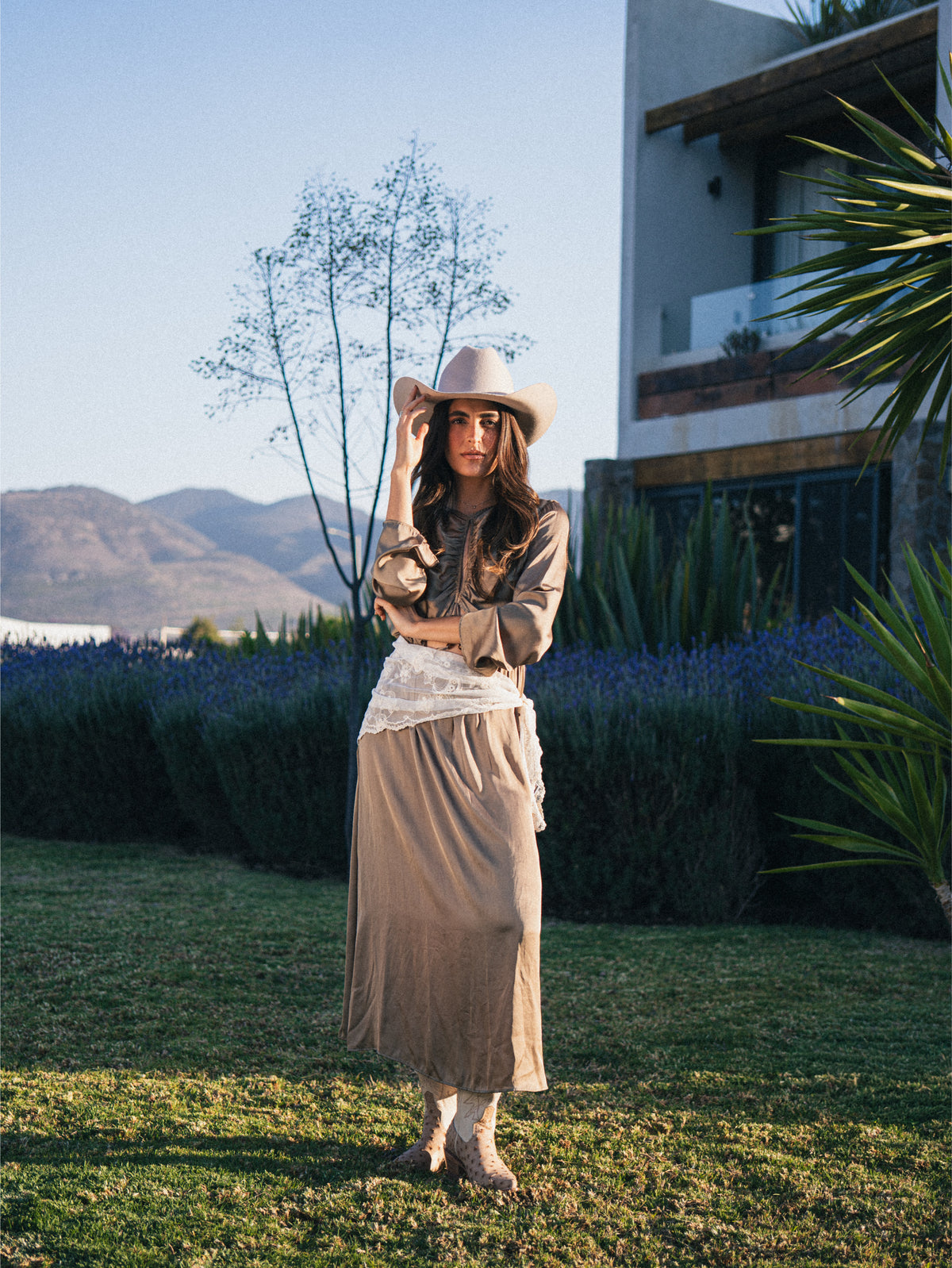 Vaquera con sombrero, falda clara y botas en una campaña de la marca.