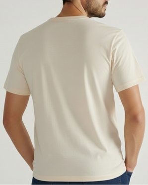 Un hombre de espaldas a la cámara viste la camiseta VAQUERO VAQUERA Beige Tee y pantalones oscuros sobre un fondo claro.